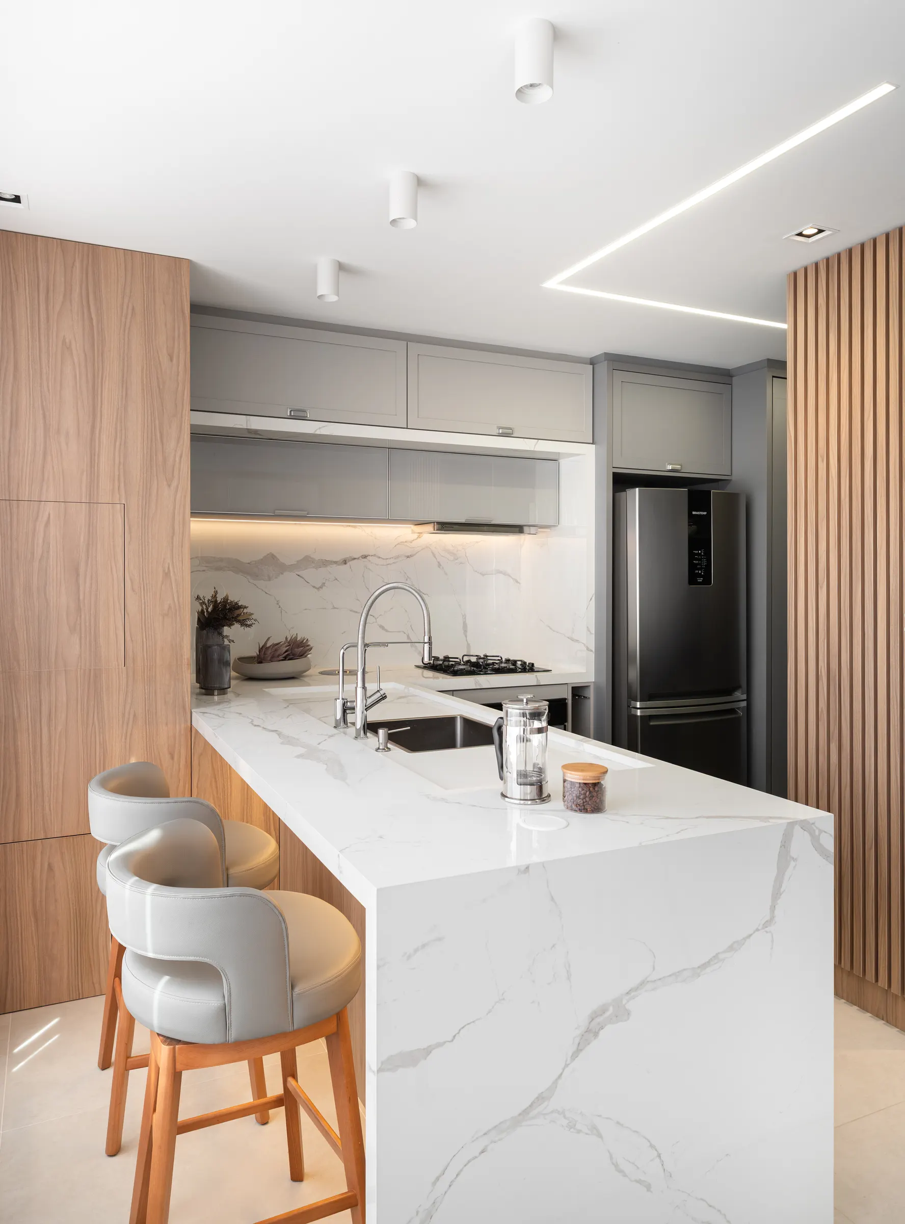 Cozinha do Apartamento 601 com ilha em pedra, marcenaria cinza e ripado de carvalho