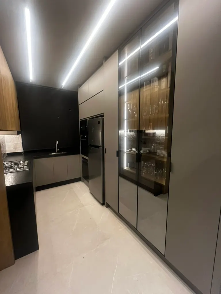 Cozinha da Casa SG com torre em vidro fumê, bancada em pedra e marcenaria sob medida em carvalho